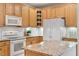 A functional kitchen with wooden cabinets, granite counters, and white appliances at 4724 Ludwell Branch Ct, Raleigh, NC 27612