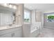 Bright bathroom featuring a soaking tub, large window, and a vanity with a white countertop at 4896 Grosbeak Ct, Mebane, NC 27302