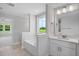 Bright bathroom featuring a soaking tub, large window, and a vanity with a white countertop at 4896 Grosbeak Ct, Mebane, NC 27302
