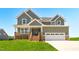 Inviting two-story home featuring a stone-accented porch and a two-car garage, set against a bright blue sky at 4896 Grosbeak Ct, Mebane, NC 27302