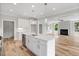 Bright, open kitchen featuring white cabinets, stainless steel appliances, and an island with a sink and quartz countertop at 4896 Grosbeak Ct, Mebane, NC 27302