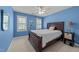 Comfortable bedroom with a dark wood bed frame, bright blue walls, and two windows that provide natural light at 5109 Makena Dr, Raleigh, NC 27615