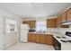 Functional kitchen with wooden cabinets and white appliances, including a microwave and stove at 555 Dacian Rd, Raleigh, NC 27610