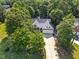 Aerial view of a home nestled among lush green trees, featuring a long driveway and two-car garage at 59 Carrousel Ct, Angier, NC 27501