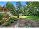 Lush backyard featuring mature trees, a stone pathway, and a storage shed at 59 Carrousel Ct, Angier, NC 27501