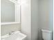 A bathroom featuring a white sink, mirror, and toilet, with neutral-colored walls at 605 Sexton Ave, Zebulon, NC 27597