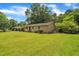 Side angle of brick home with a green yard and mature trees in a quiet neighborhood at 605 Sexton Ave, Zebulon, NC 27597