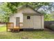 Backyard with a wood deck and small, square window on the side of the beige single-story home at 611 Rowland St, Henderson, NC 27536