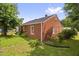 Back view of brick home with green grass and flower garden in the back yard at 625 Columbia Ave, Burlington, NC 27217