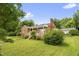 Quaint brick home with a covered front porch, an American flag, and a well-maintained lawn with mature trees at 625 Columbia Ave, Burlington, NC 27217
