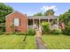 Charming red brick home featuring a cozy front porch and a well-maintained lawn with mature landscaping at 625 Columbia Ave, Burlington, NC 27217