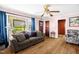 Comfortable living room featuring hardwood floors, a plush sofa, large window, and a classic ceiling fan at 625 Columbia Ave, Burlington, NC 27217