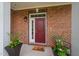 Charming brick home with a red front door and decorative potted plants on a sunny porch at 10310 Sablewood Dr # 111, Raleigh, NC 27617