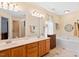 Bathroom with dual sinks, tub, and vanity with decorative hardware, bright vanity lighting at 107 Canyon Run, Cary, NC 27513