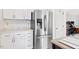 Modern kitchen featuring stainless steel refrigerator, white cabinets, and quartz countertops with easy access to living area at 107 Canyon Run, Cary, NC 27513