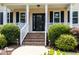 Inviting front porch with brick steps, white railings, and tasteful landscaping for curb appeal at 113 Sycamore Ridge Ln, Holly Springs, NC 27540