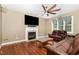 Inviting room with a fireplace, wood floors, ceiling fan, and comfortable seating arrangement at 113 Sycamore Ridge Ln, Holly Springs, NC 27540