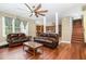 Inviting living room with leather sofas, wood floors, and a ceiling fan at 113 Sycamore Ridge Ln, Holly Springs, NC 27540