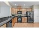 Well-equipped kitchen with wooden cabinets, black appliances, granite countertops, and ample storage space for cooking at 128 Arvind Oaks Cir, Cary, NC 27519