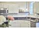 Well-lit kitchen featuring white cabinets, stainless steel appliances, and black countertops at 142 College Ave Ave, Durham, NC 27713