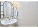 Neat powder room includes a pedestal sink, arched mirror, and a neutral color palette at 142 College Ave Ave, Durham, NC 27713