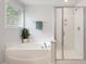 Bathroom featuring a soaking tub, a separate glass-enclosed shower, and a window at 143 Thornbury St, Clayton, NC 27527