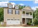 Charming two-story home with a white garage door, beautiful plants, and second story porch at 143 Thornbury St, Clayton, NC 27527