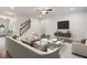 Bright living room with white furniture, hardwood floors, fireplace, and staircase at 143 Thornbury St, Clayton, NC 27527