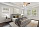 Bright main bedroom featuring hardwood floors, tray ceiling with fan, and neutral color scheme at 143 Thornbury St, Clayton, NC 27527