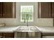 Stainless steel farmhouse sink below window offers modern touch and backyard views at 150 Will Woods Way, Franklinton, NC 27525