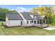 View of the rear of the house, with a stone patio, covered porch, manicured lawn and landscaping, offering luxury and tranquility at 15517 Possum Track Rd, Raleigh, NC 27614
