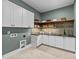 Well-organized laundry room features upper and lower cabinets, quartz counters, floating shelves, and charming herringbone floors at 15517 Possum Track Rd, Raleigh, NC 27614