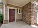 Inviting front entrance with a maroon door, sidelight, stone accents, and covered porch at 1604 Vineyard Mist Dr, Cary, NC 27519