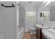 Bathroom featuring double sinks with wood vanity, toilet, tub and shower combo, and window at 1818 Cecil St, Durham, NC 27707