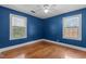 Bright blue bedroom with hardwood floors, ceiling fan, and two windows at 1818 Cecil St, Durham, NC 27707