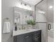 Modern bathroom vanity with a large mirror, lighting, and a tiled shower at 2100 Summit St, Durham, NC 27707
