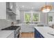 Bright kitchen showcasing stainless steel appliances, a farmhouse sink, and a blue island with seating at 2100 Summit St, Durham, NC 27707
