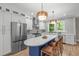 Open kitchen with stainless steel refrigerator, island with seating, and wooden pendant lighting at 2100 Summit St, Durham, NC 27707