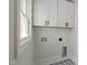Efficient laundry room with patterned tile, utility connections, and ample white cabinet space at 2100 Summit St, Durham, NC 27707