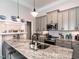 Kitchen island with granite countertops, stainless steel sink, and gray cabinets at 212 W Church St, Benson, NC 27504