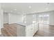 Bright and airy kitchen with white cabinets, a granite island, and sleek wood-look flooring throughout the main living spaces at 287 South Breeze Way, Fuquay Varina, NC 27526