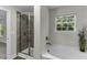 Well-lit bathroom featuring a shower, tub, tile accents, and a large window at 301 Sawgrass Ct, Mebane, NC 27302