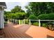 A spacious wooden deck with black metal railings and chairs surrounded by green lawn and trees at 3021 Glenwood Dr, Durham, NC 27705