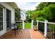 A patio set on a deck with a potted plant next to a house and green trees at 3021 Glenwood Dr, Durham, NC 27705