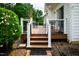 A wooden deck with black metal railings and outdoor furniture, extending from a white home with a manicured lawn at 3021 Glenwood Dr, Durham, NC 27705