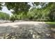 Outdoor sand volleyball court surrounded by mature trees and a pool in the background at 304 Cayman Ave, Holly Springs, NC 27540