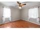 Cozy bedroom with laminate floors, large windows dressed with white curtains, and a ceiling fan at 304 Westfield Dr, Dunn, NC 28334