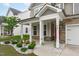 Charming home exterior with a covered front porch, stone accents, and landscaped garden at 309 Highland Forest Dr, Fuquay Varina, NC 27526