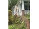 Side of a bungalow with a brick chimney and overgrown yard and plants around the foundation at 431 Charles St, Henderson, NC 27536