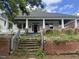 Bungalow with brick foundation, overgrown yard and stairs leading to a covered front porch with columns at 431 Charles St, Henderson, NC 27536